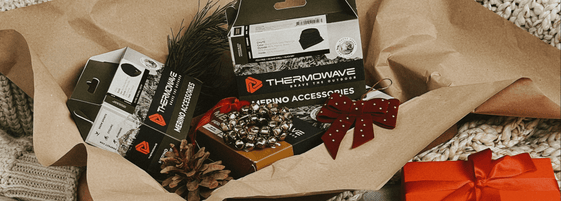 woman holding a full gift box with thermowave clothing and Christmas decorations