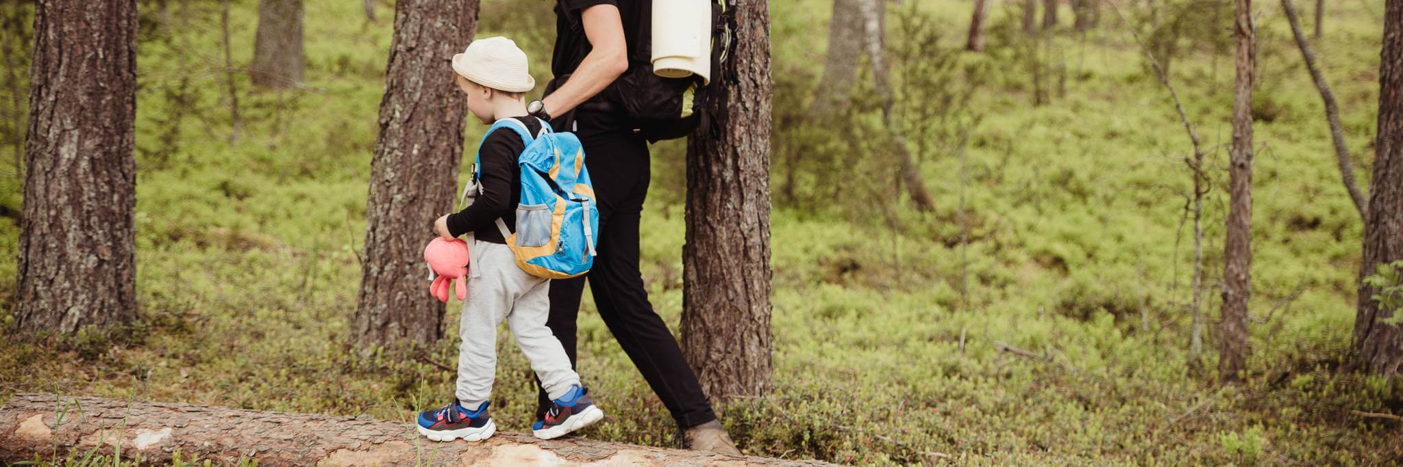 A boy is holding his father's hand and going to hike in the forest