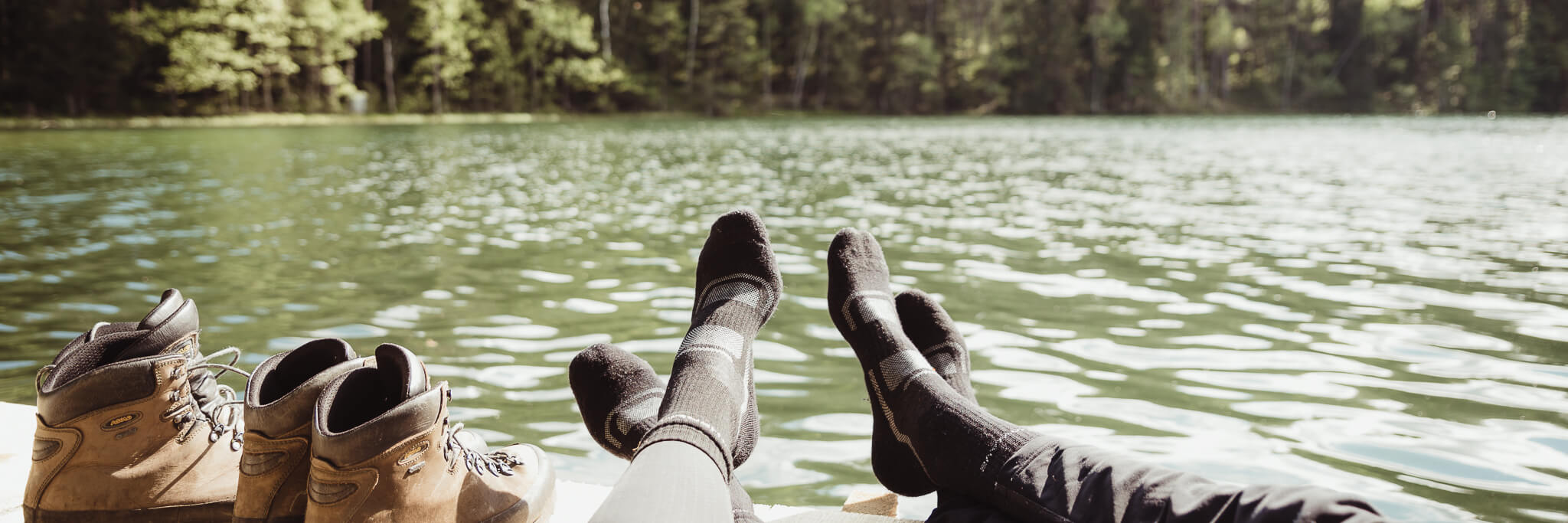two-people-sitting-and-resting-by-the-lake-during-hike