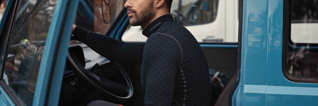 A man is sitting in the old car and wearing a black Merino Xtreme shirt