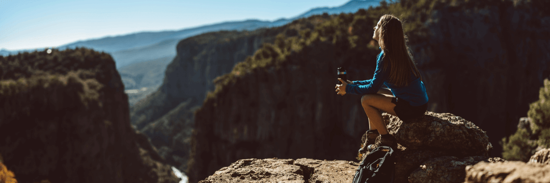 A woman in the mountain is resting, sitting on the stone