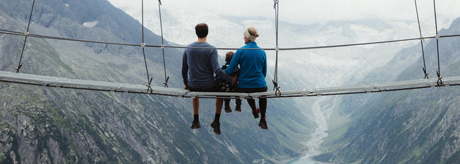 A family sits on a bridge over a mountain gorge