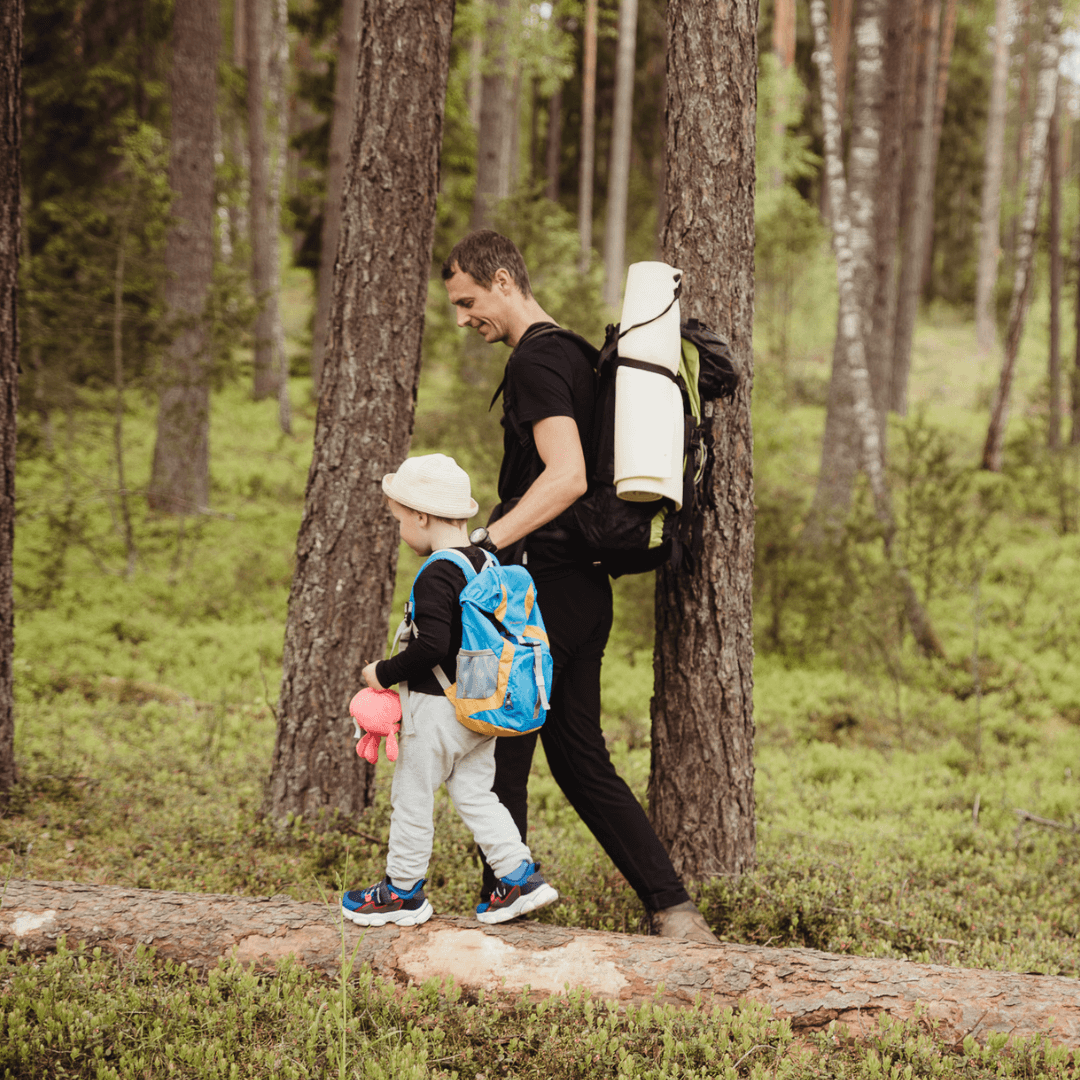 A boy is holding his father's hand and going to hike in the forest