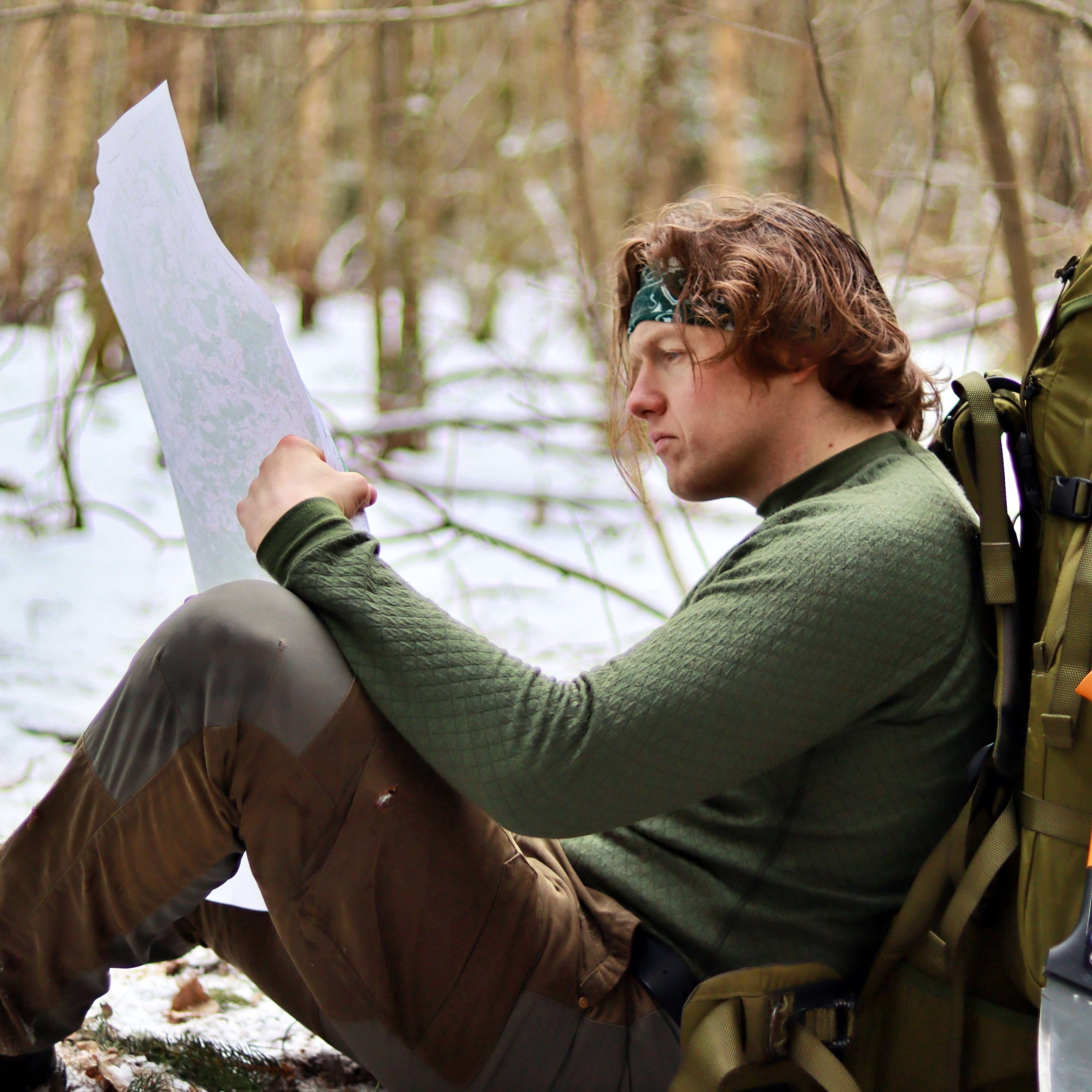 a-man-sitting-and-checking-map-in-the-forest-at-winter