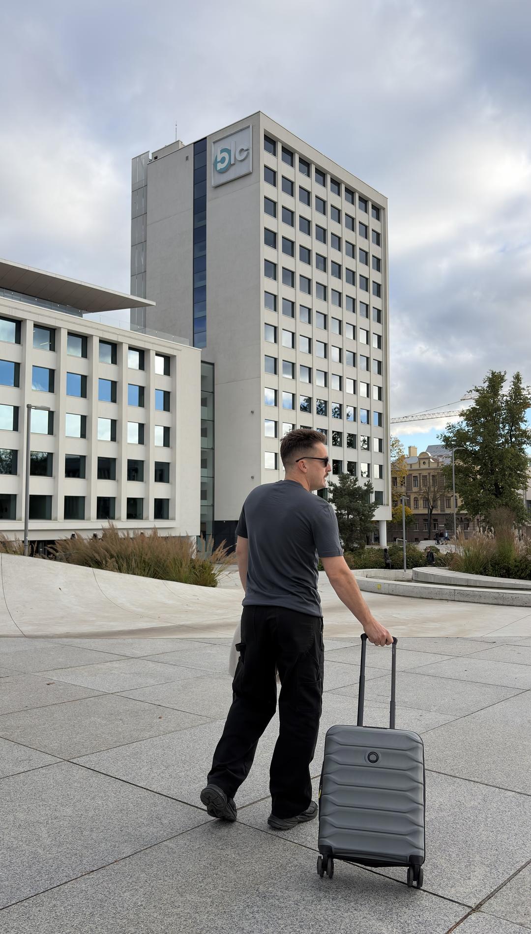 Traveller with a carry-on suitcase in the city, wearing the Merino Life Tee