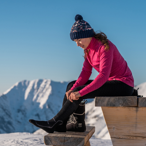 a-woman-in-the-mountains-sits-on-a-wooden-table-and-puts-on-socks